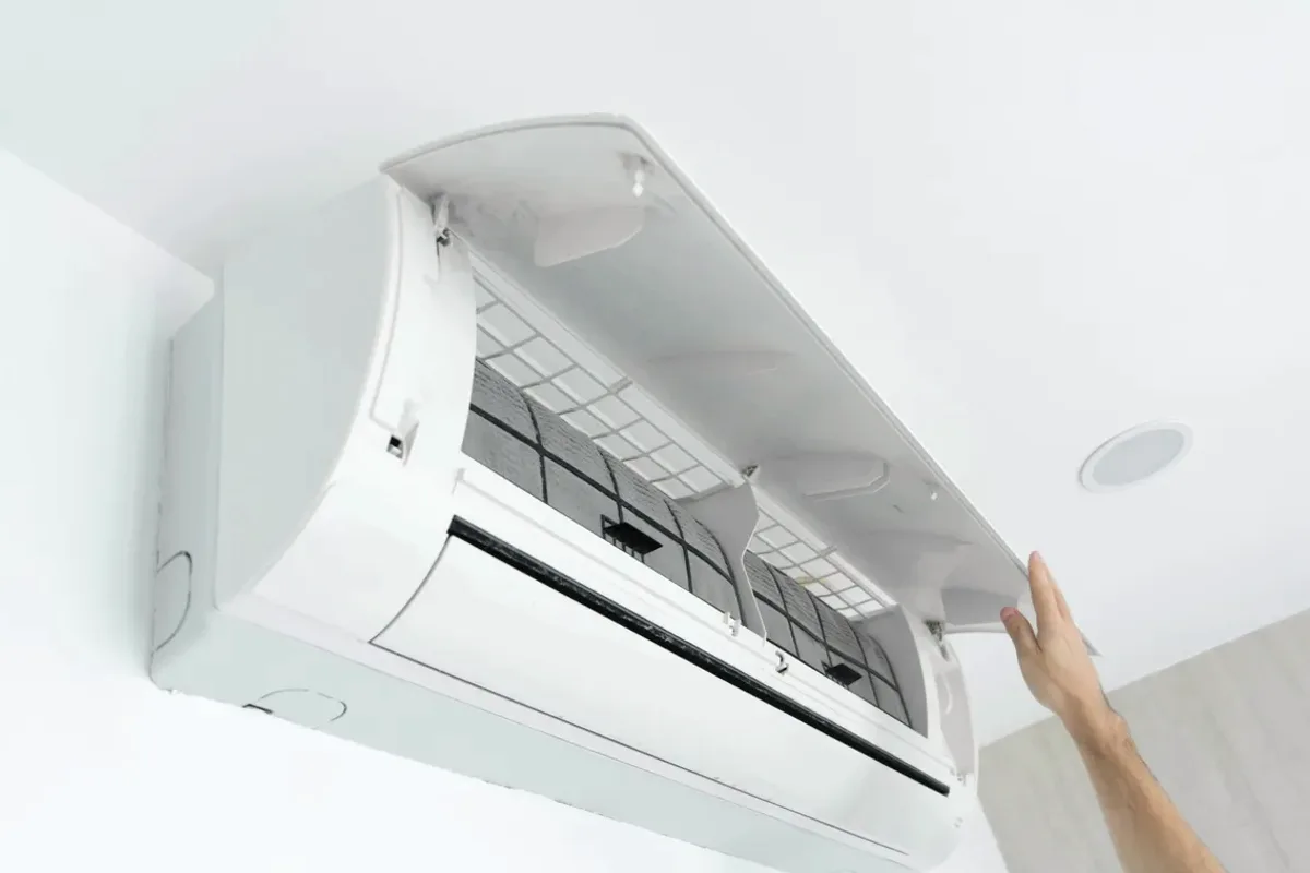 Hand opening the cover of a wall-mounted ductless air conditioner